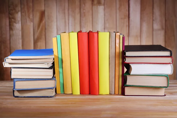 Boeken over houten tafel op houten muur achtergrond — Stockfoto