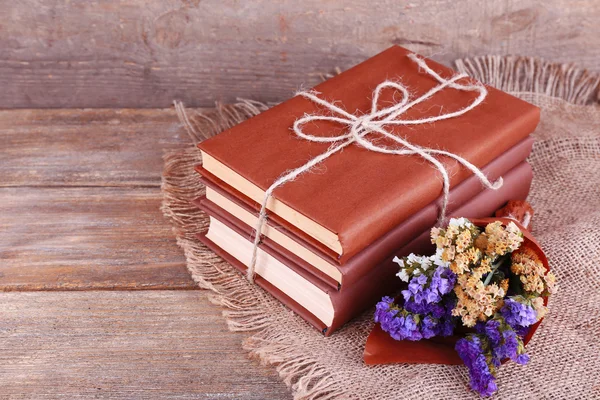 Böcker och blommor på servett på träbord på trävägg bakgrund — Stockfoto