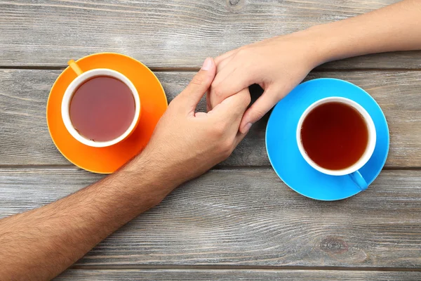 Loving couple with hot drinks on table — Stock Photo, Image