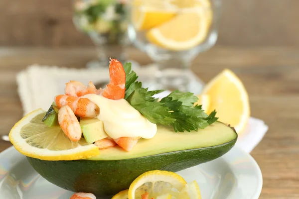 Ensalada sabrosa con gambas y aguacate en plato, sobre fondo de madera — Foto de Stock