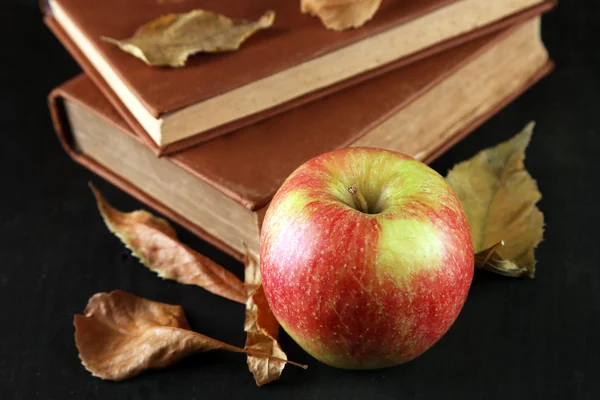 Яблоко с книгами и сухими листьями на фоне дерева — стоковое фото