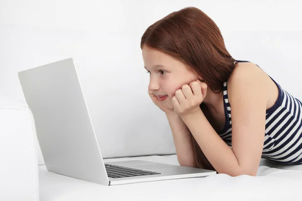 Menina bonita com laptop no sofá no quarto — Fotografia de Stock