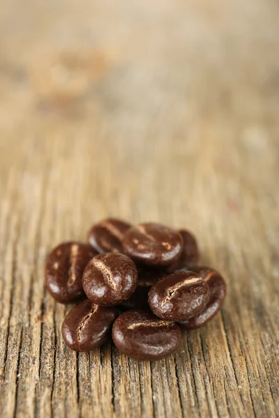 Kaffeebohnen mit Schokoladenglasur auf Holzgrund — Stockfoto