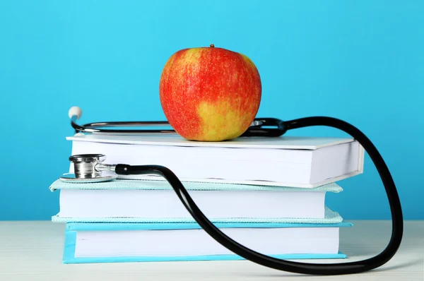 Medizinisches Stethoskop mit Apfel und Büchern — Stockfoto