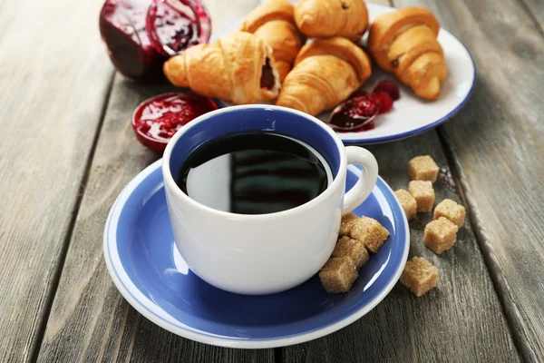 Café da manhã com chá, geléia de framboesa e croissants frescos em fundo de madeira — Fotografia de Stock