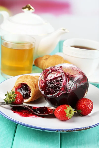 Desayuno con té, zumo de manzana, mermelada y croissants frescos sobre mesa de madera, sobre fondo brillante — Foto de Stock