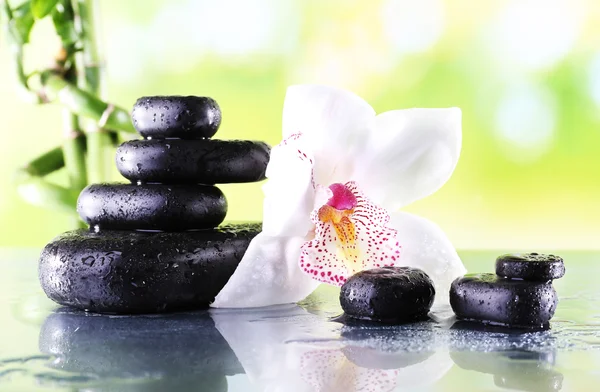 Piedras de spa y orquídea blanca sobre mesa sobre fondo natural —  Fotos de Stock