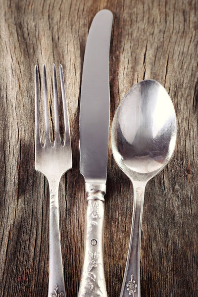 Металлический нож, ложка и вилка на деревянном фоне
