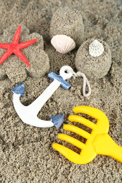 Песок в форме цветов и замка, морские звезды и детские игрушки крупным планом — стоковое фото