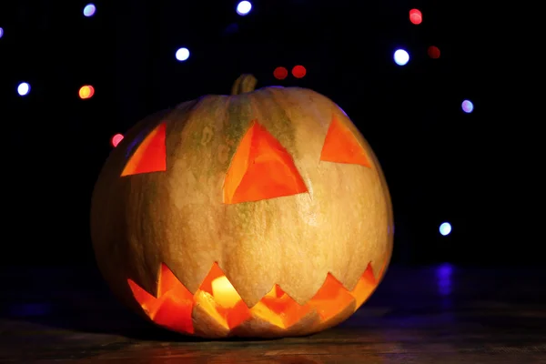 Abóbora de Halloween na mesa no fundo escuro com luzes multicoloridas — Fotografia de Stock