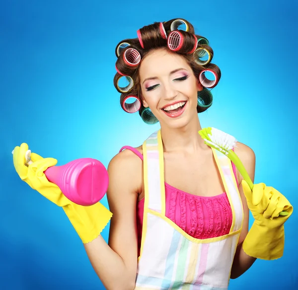 Menina bonita em encrespadores de cabelo no fundo azul — Fotografia de Stock