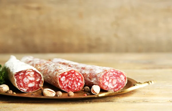 Italienische Salami auf Tablett, auf Holzgrund — Stockfoto
