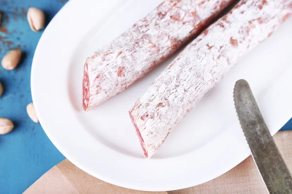 Italian salami on plate,  on wooden background — Stock Photo, Image