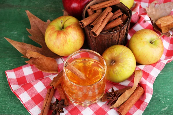 Skład jabłek w szkle z cynamonu, świeże jabłka i liści jesienią na drewniane tła — Zdjęcie stockowe