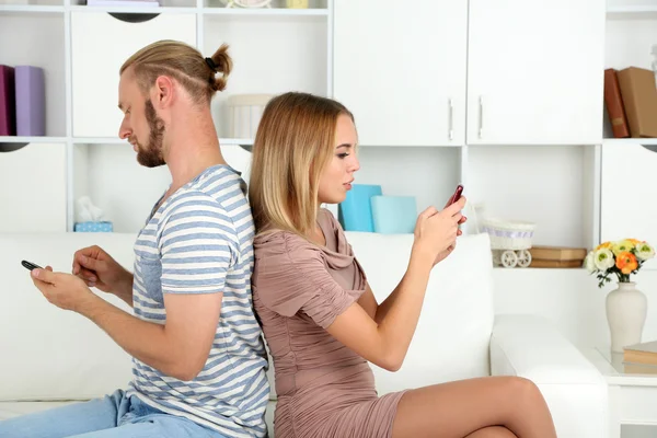 Jovem casal após briga enviando mensagens uns aos outros em casa — Fotografia de Stock