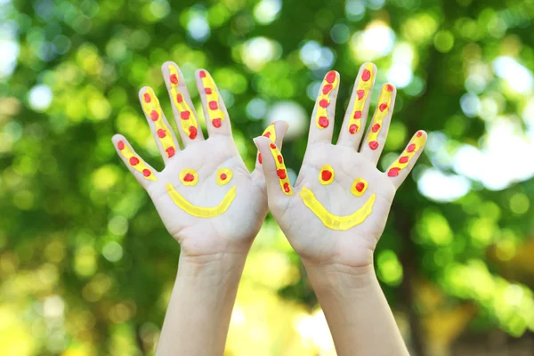 Sorrindo mãos coloridas sobre fundo natural — Fotografia de Stock