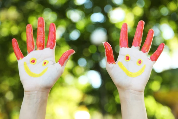 Sorrindo mãos coloridas sobre fundo natural — Fotografia de Stock
