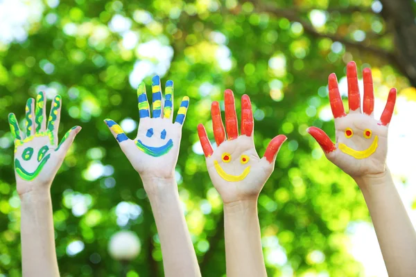 Smiling colorful hands on natural background — Stock Photo, Image