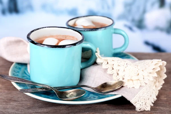 Tassen mit schmackhaftem heißem Kakao, auf Holztisch, auf hellem Hintergrund — Stockfoto