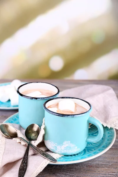 Tassen mit schmackhaftem heißem Kakao, auf Holztisch, auf hellem Hintergrund — Stockfoto