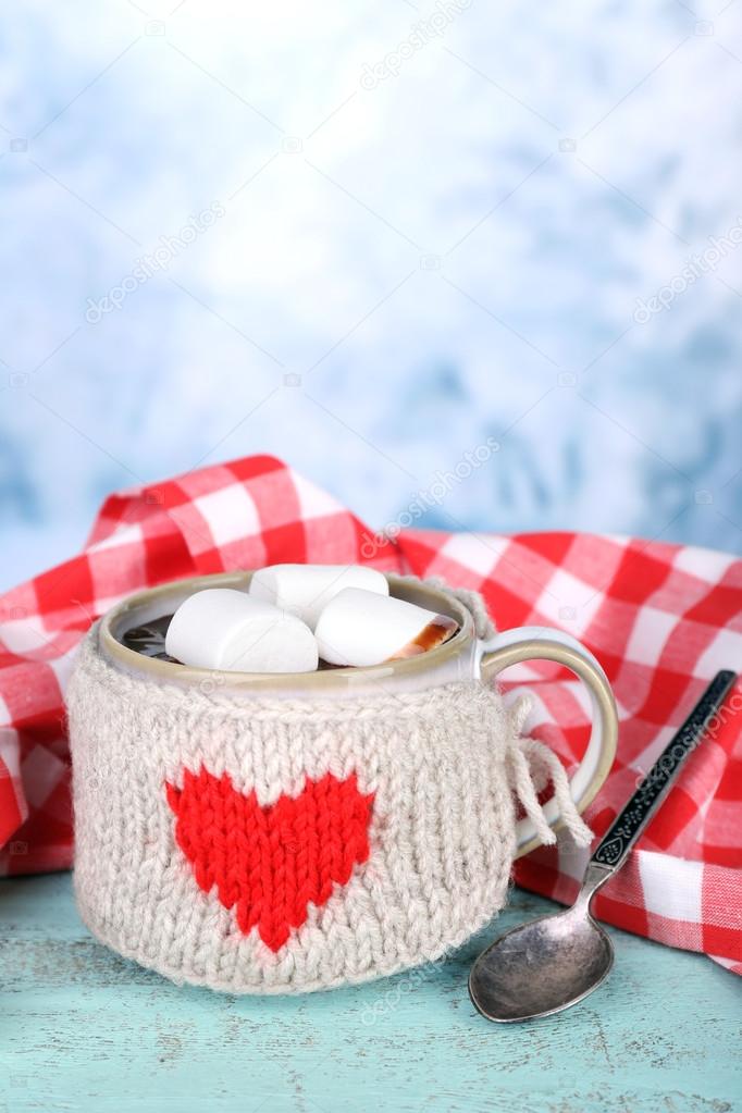 Cup of tasty hot cocoa, on wooden table, on light background