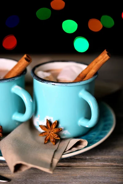 Tassen mit leckerem heißem Kakao, auf Holztisch, auf glänzendem Hintergrund — Stockfoto