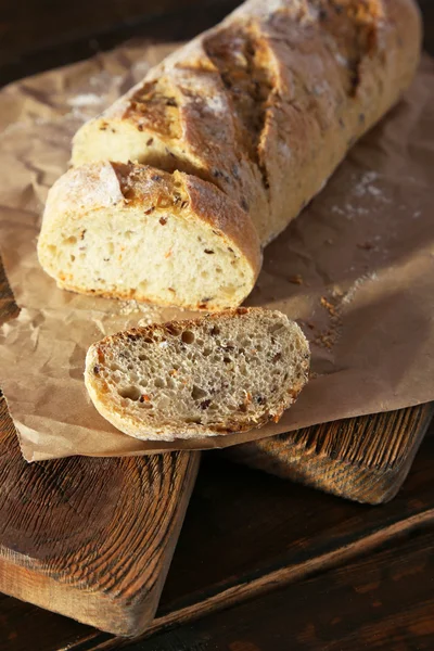 Geschnittenes Weißbrot und Messer auf Bastelpapier auf Schneidebrett auf Holzgrund — Stockfoto