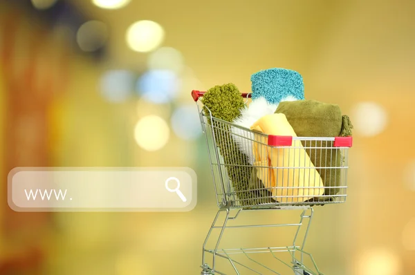 Shopping concept. Shopping cart with colorful carpets and plaids on shop background — Stock Photo, Image