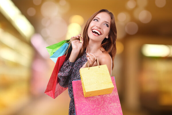 Shopping concept. Beautiful young woman with shopping bags on bright background