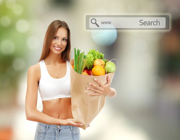 Shopping concept. Beautiful young woman with vegetables and fruits in shopping bag on shop background