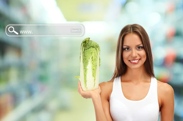 Shopping concept. Beautiful young woman with cabbage on shop background — Stock Photo, Image