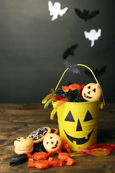 Diferentes dulces para fiesta de Halloween en mesa de madera, sobre fondo oscuro — Foto de Stock