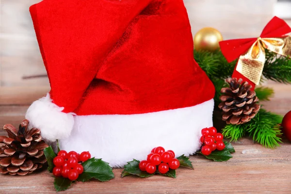 Leaves of mistletoe with Christmas hat on table close-up — Stock Photo, Image