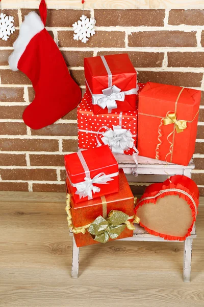 Weihnachtsgeschenke auf Standleiter auf braunem Backstein-Hintergrund — Stockfoto