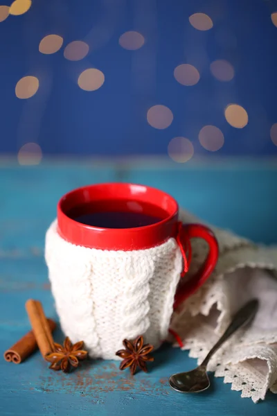 Tasse schmackhaften heißen Tee, auf Holztisch, auf glänzendem Hintergrund — Stockfoto