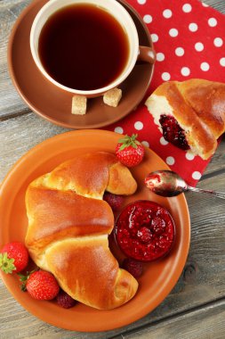 Çay ve ahşap arka plan üzerinde büyük taze kruvasan kahvaltı