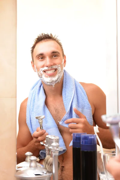 Jeune homme rasant sa barbe dans la salle de bain — Photo