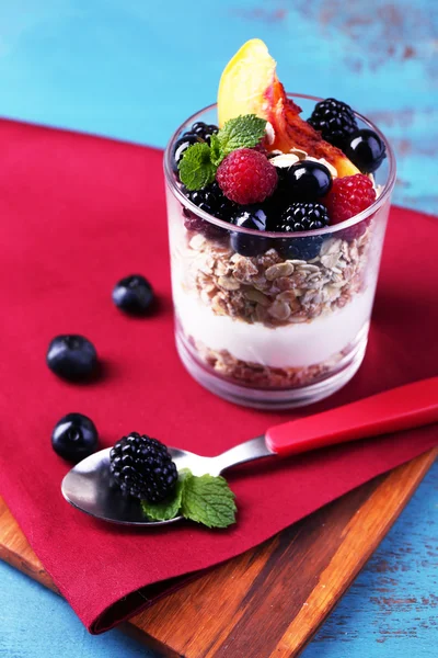 Egészséges - joghurt, friss gyümölcsök, bogyók, müzli, reggeli üveg, színes fából készült háttér — Stock Fotó