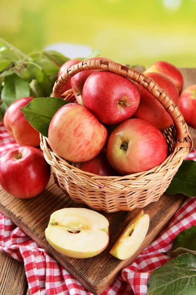 Manzanas dulces en canasta de mimbre sobre mesa sobre fondo brillante — Foto de Stock