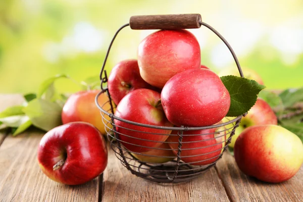 Söta äpplen i flätade korgen på bordet på ljus bakgrund — Stockfoto