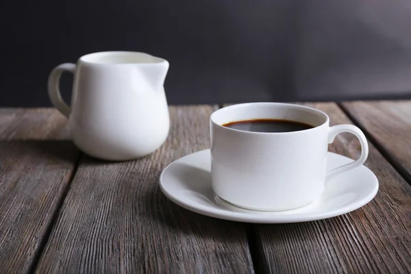 Kopje koffie en room in Melkkannetje op houten tafel op donkere achtergrond — Stockfoto