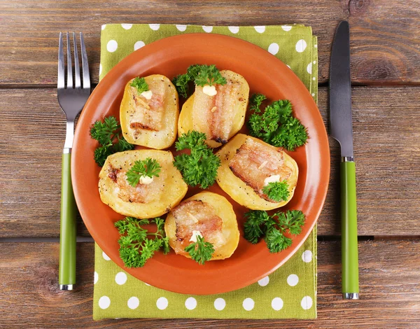 Baked potato with bacon on plate, on wooden background — Stock Photo, Image