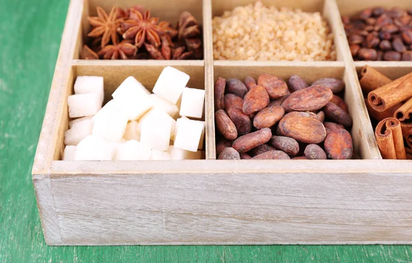 Caja de madera con set de café y granos de cacao, terrones de azúcar, chocolate negro, canela y anís sobre fondo de madera — Foto de Stock