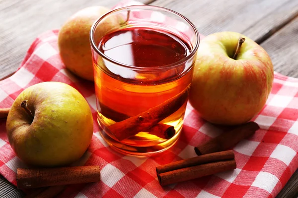 Apple cider med kanelstänger och färska äpplen på trä bakgrund — Stockfoto