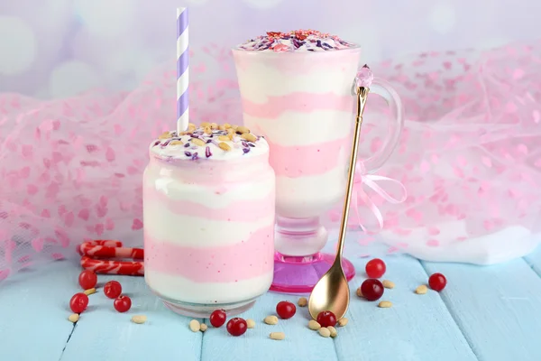 Postre de leche de arándano en frasco de vidrio y vidrio, sobre mesa de madera de color, sobre fondo claro —  Fotos de Stock