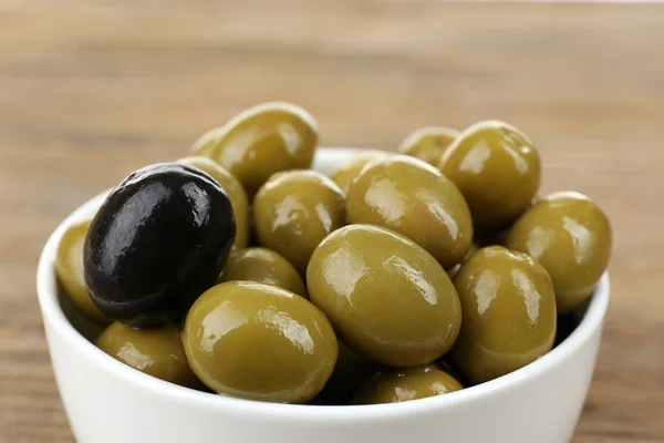 Individuality concept. Olive in bowl on wooden table — Stock Photo, Image