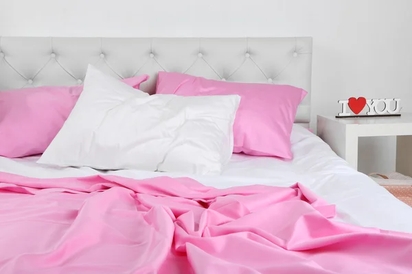 Ropa de cama arrugada rosa en la cama — Foto de Stock