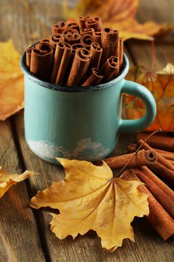 Ahşap zemin üzerine sarı yaprakları ile bardağa tarçın sopa