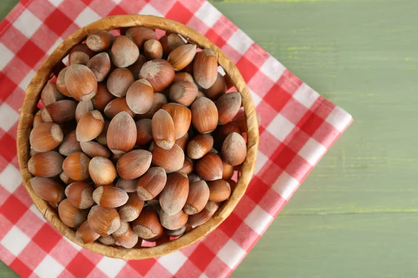Hazelnuts on wicker mat on wooden background — Stock Photo, Image