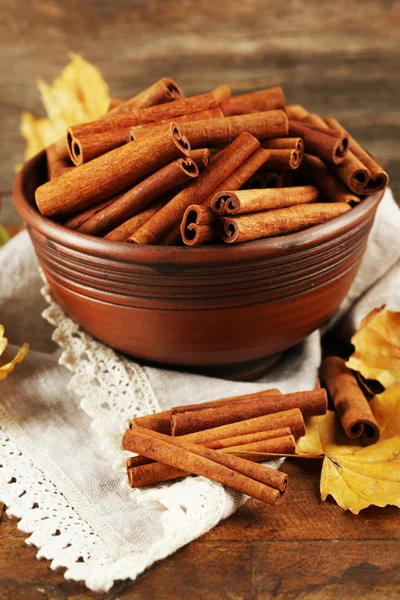 Ahşap zemin üzerine sarı yaprakları ile kase tarçın sopa